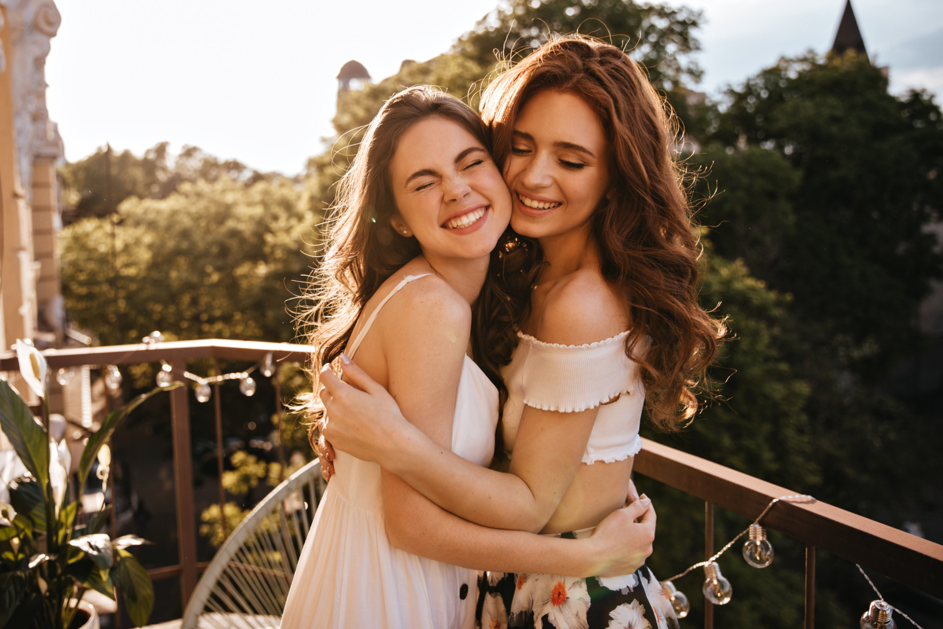 zwei junge Frauen die sich mit geschlossenen Augen umarmen und lächeln